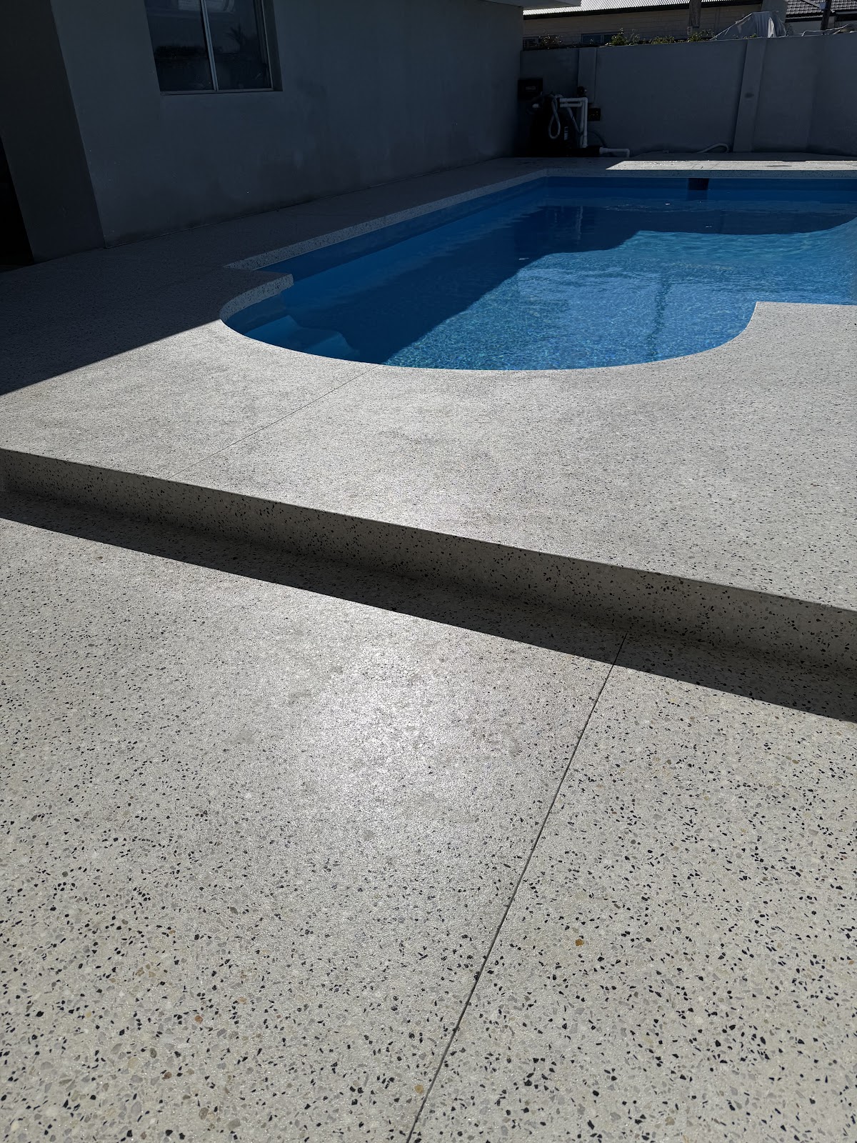 Honed pool surround with a formed step down, kidney pool behind