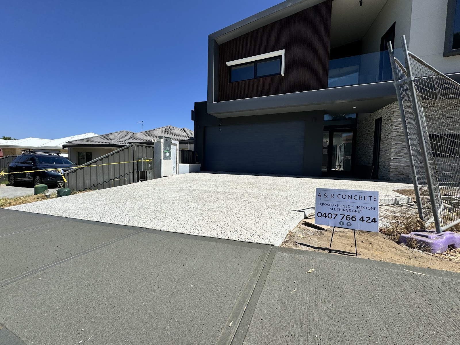 Fresh exposed aggregate driveway at a new two-storey build, A&R Concrete site sign out front