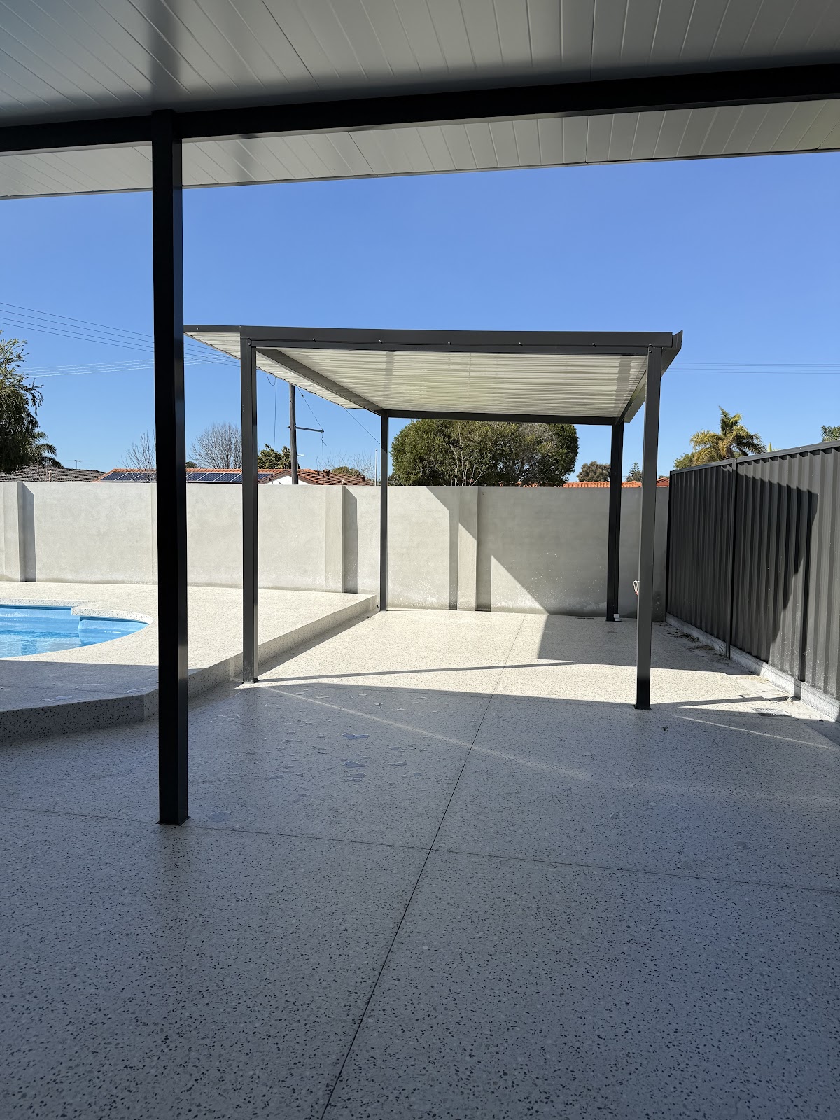 Honed concrete around a pool and under a new pergola frame