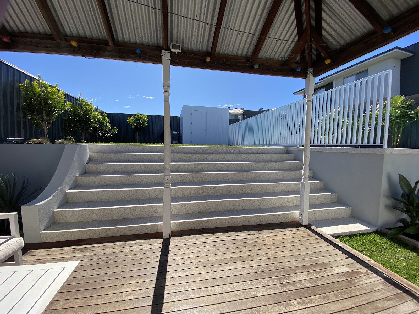 White honed concrete steps rising from a timber deck to the lawn