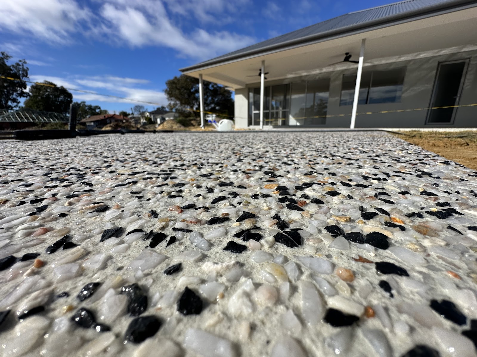 Exposed aggregate close up, black and white stone mix, covered patio behind