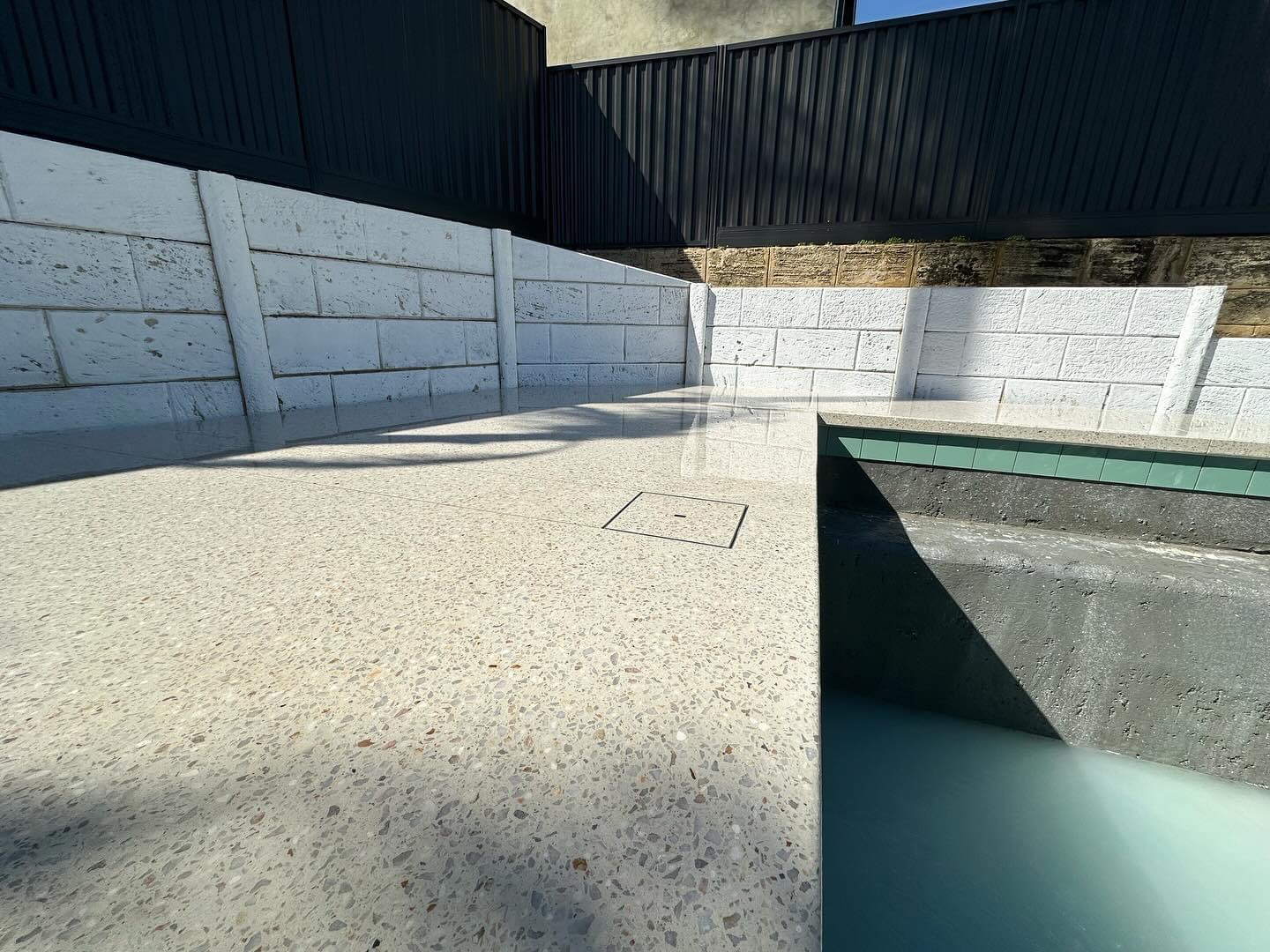 Honed surround at a plunge pool against white block retaining walls