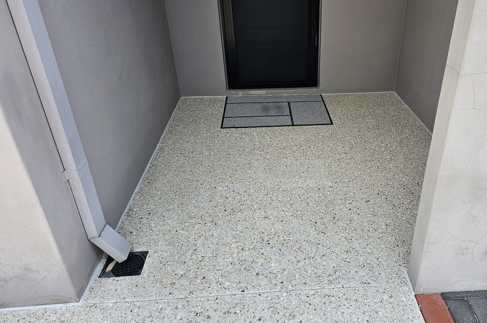 Front porch in exposed aggregate with a charcoal inset entry mat detail
