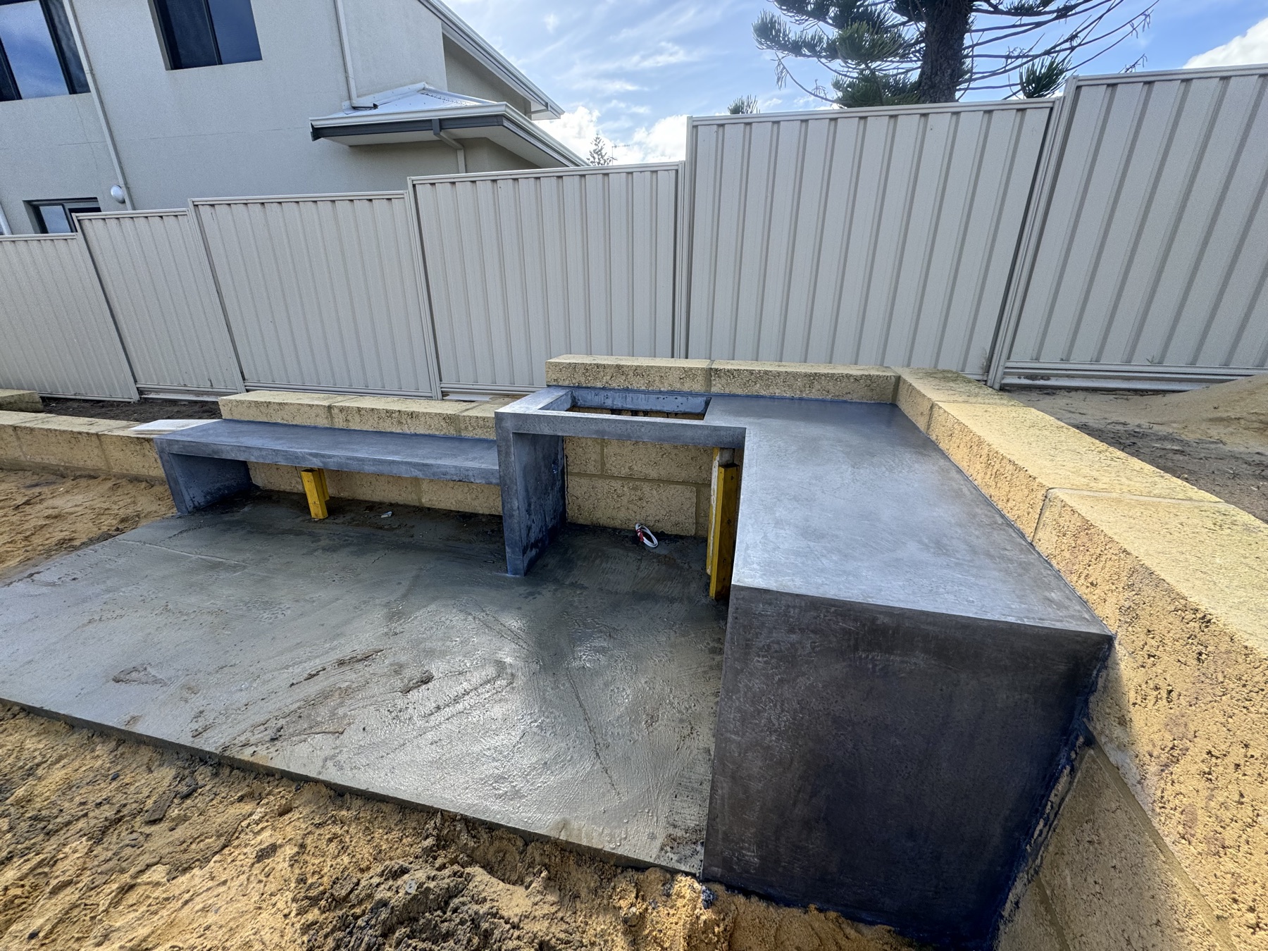 Concrete bench seat and planter box cast around a new pool zone, limestone block retaining behind