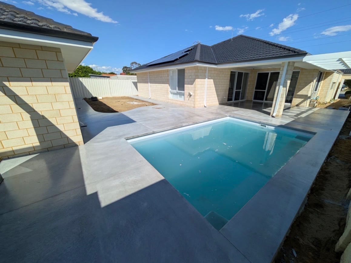 Honed concrete pool surround wrapping the water and running back to the alfresco of a new limestone block home
