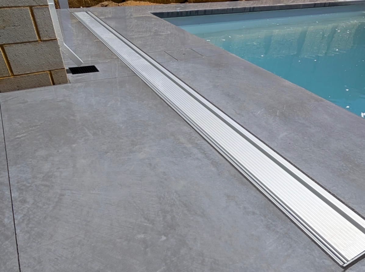 Honed pool surround with a stainless strip drain running the full length of the pool edge